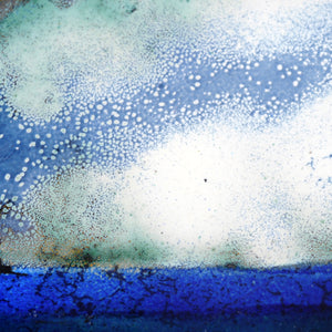 gros plan sur la partie de l'objet d'art contemporain en émaux joaillier, représentant le ciel, au dessus de la mer bleue. 