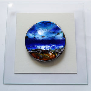 Création murale composée d'une plaque de cuivre ronde émaillée grand feu et fixée sur une plaque de verre.