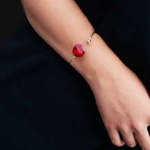 Load image into Gallery viewer, Bracelet porté  - cabochon émaillé rouge sur jonc en argent flexible - Anne de La Forge
