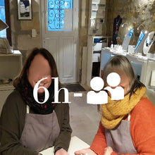Charger l&#39;image dans la galerie, deux femmes en tablier photographiées pendant leur stage de découverte aux techniques de l&#39;émaillage d&#39;art avec leur création dans la main.
